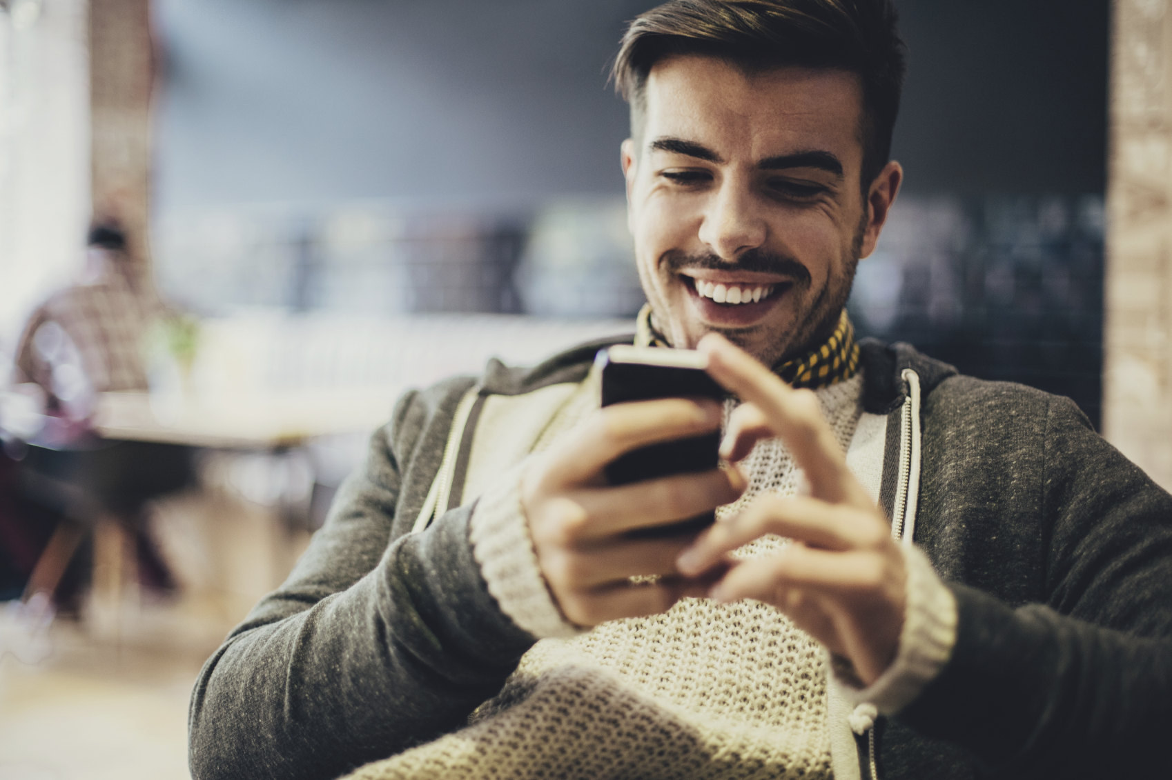 Dude smiles while looking at his smartphone